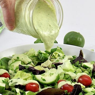 avocado ranch dressing being poured over salad