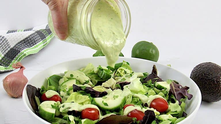 avocado ranch dressing being poured over salad