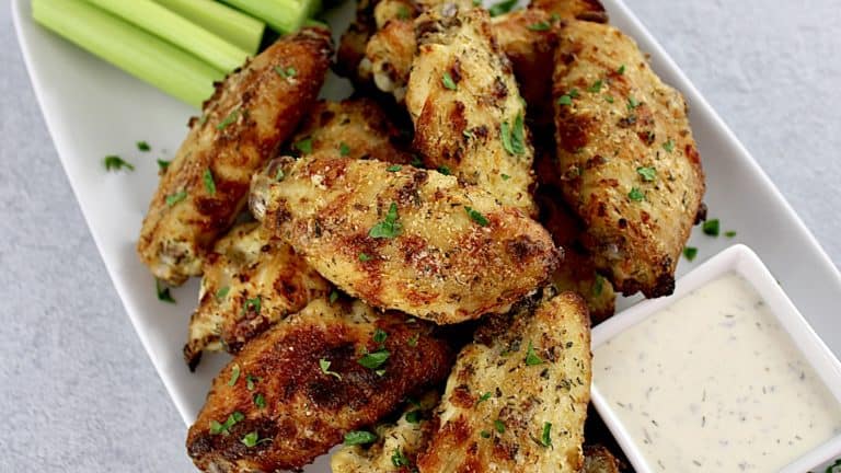 Baked Ranch Chicken Wings on white platter with ranch dressing and celery on side