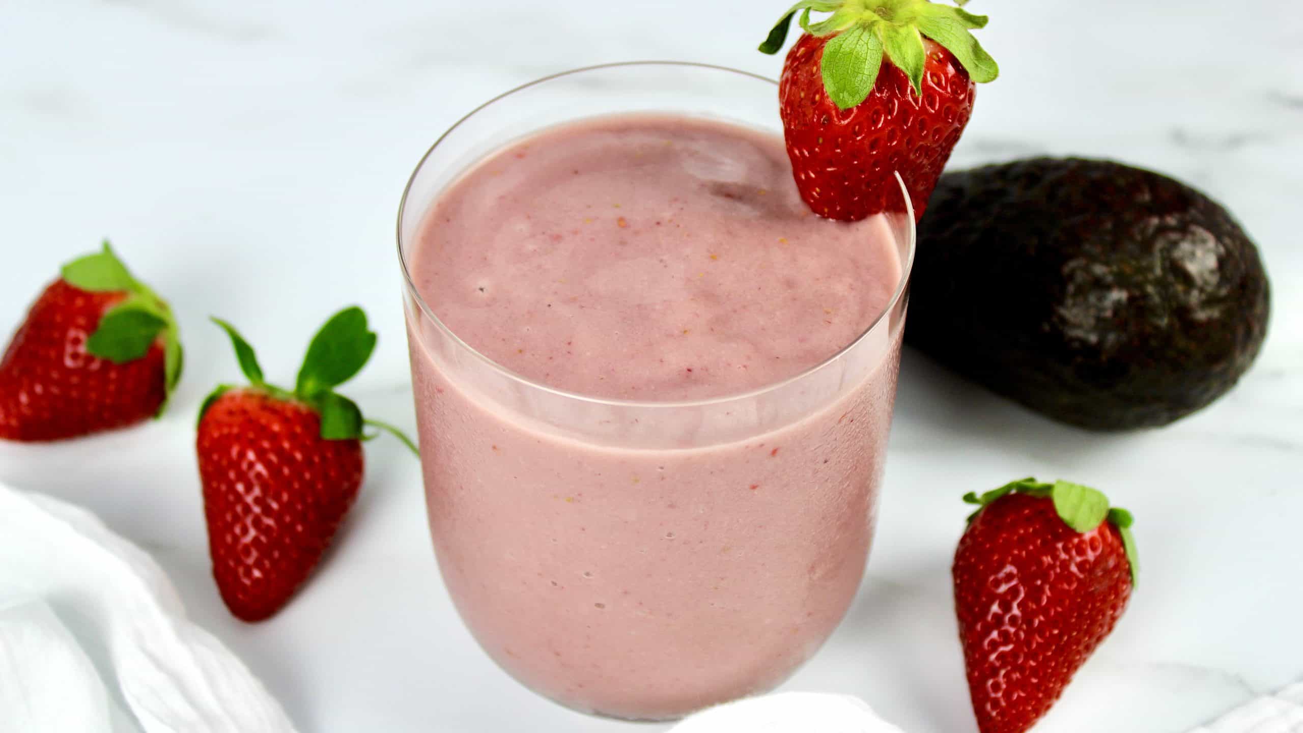 Berry Avocado Smoothie in glass with strawberry on side of glass