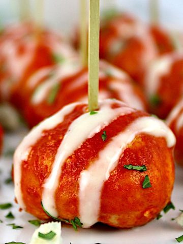 Buffalo Chicken Meatballs with blue cheese drizzled on top and toothpicks in them