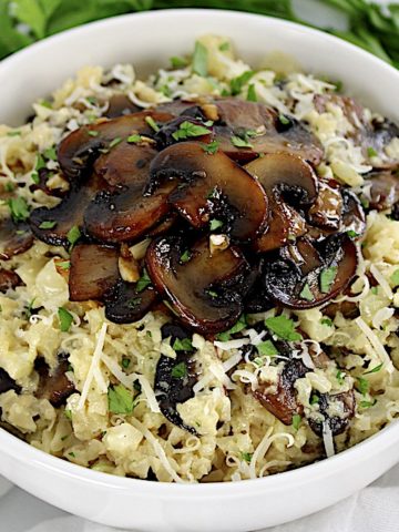 cauliflower mushroom risotto in white bowl with mushrooms on top