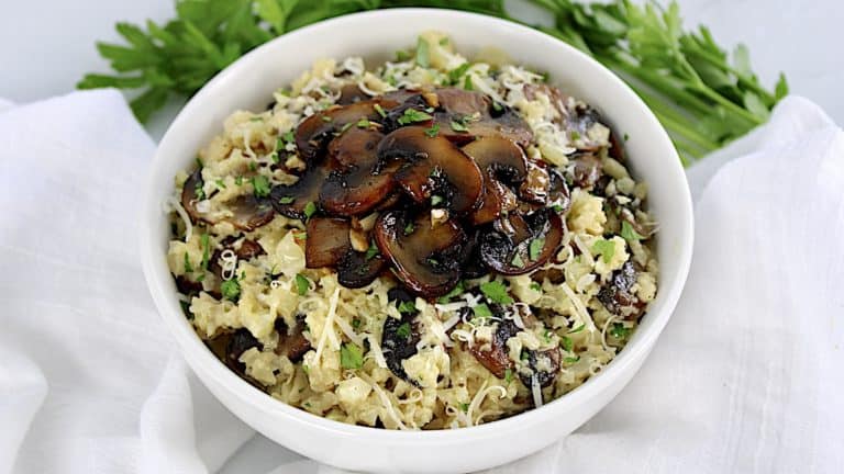 cauliflower mushroom risotto in white bowl with mushrooms on top