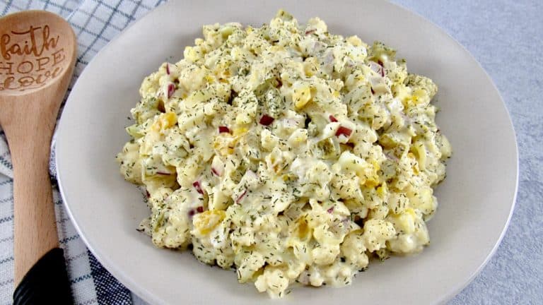 Cauliflower "Potato" Salad in bowl with wooden spoon on the side