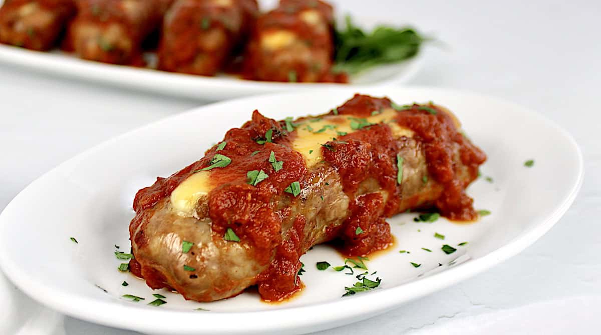 Cheese Stuffed Sausage on white plate with marinara sauce and chopped parsley on top