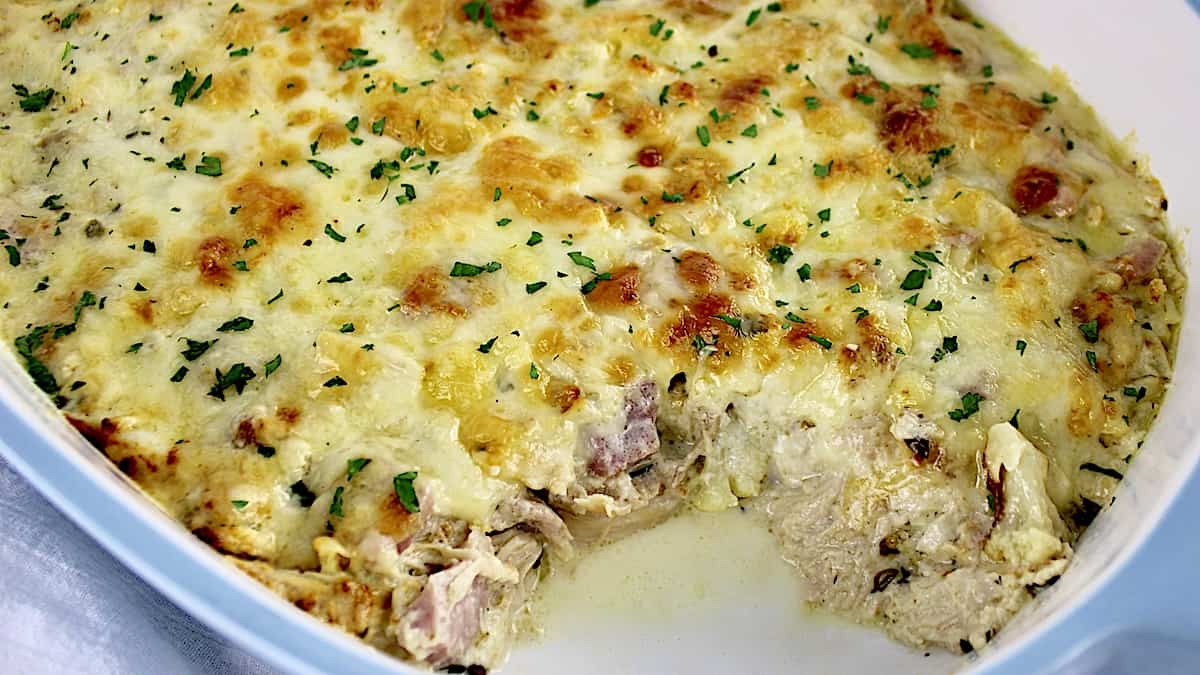 Chicken Cordon Bleu Casserole with melted cheese on top and piece missing