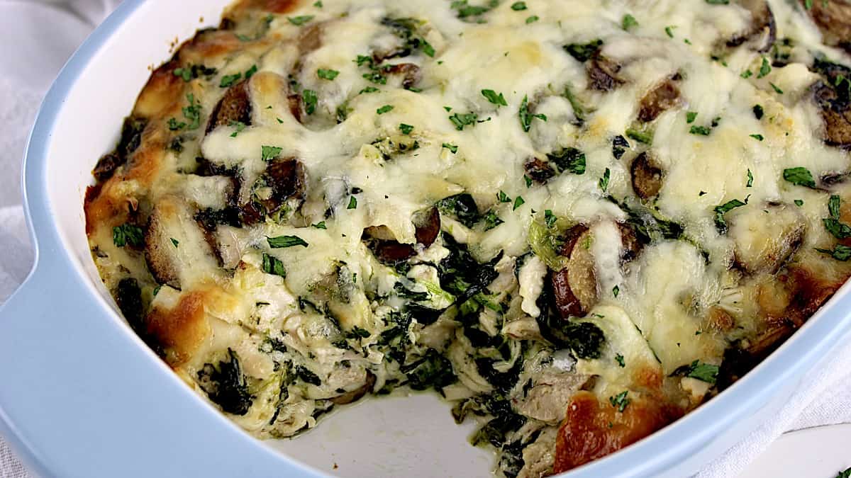 Chicken Florentine Casserole with melted cheese on top and piece missing