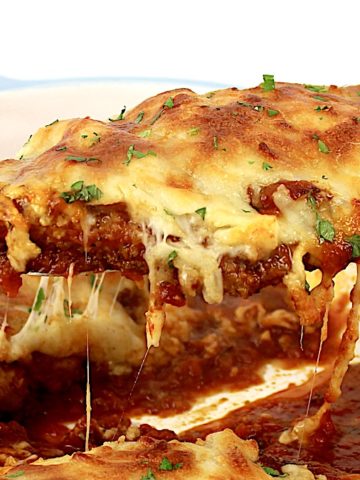 Chicken Parmesan piece being held up by silver spatula with cheese pull