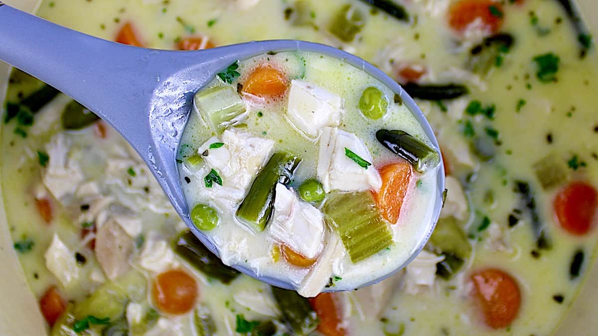 Chicken Pot Pie Soup in gray spoon over soup bowl