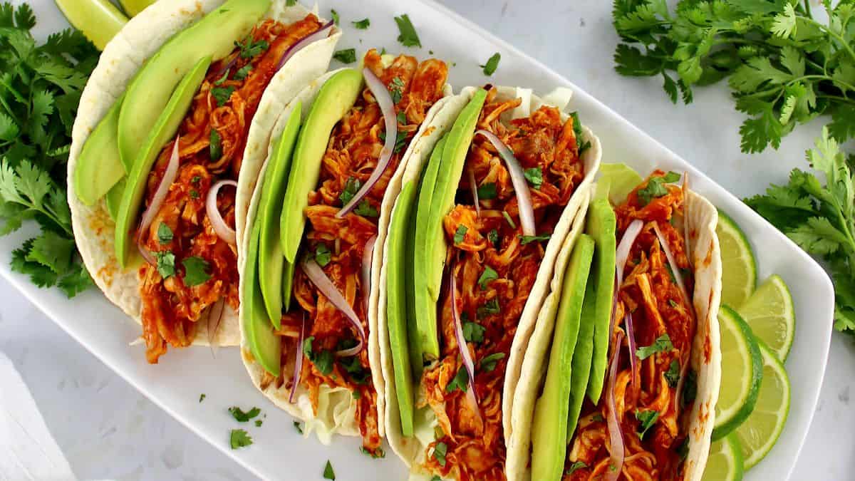 overhead view of Chicken Tinga tacos with avocado slices and red onion