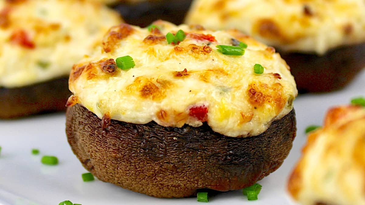 closeup of Crab Stuffed Mushrooms with chopped chives on white plate