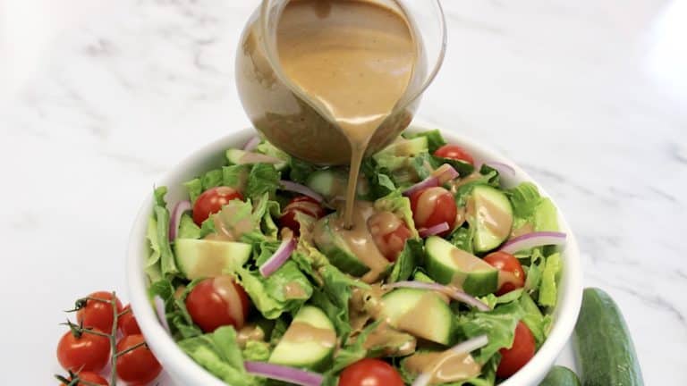 Lemon Poppy Seed Dressing being poured over salad in white bowl