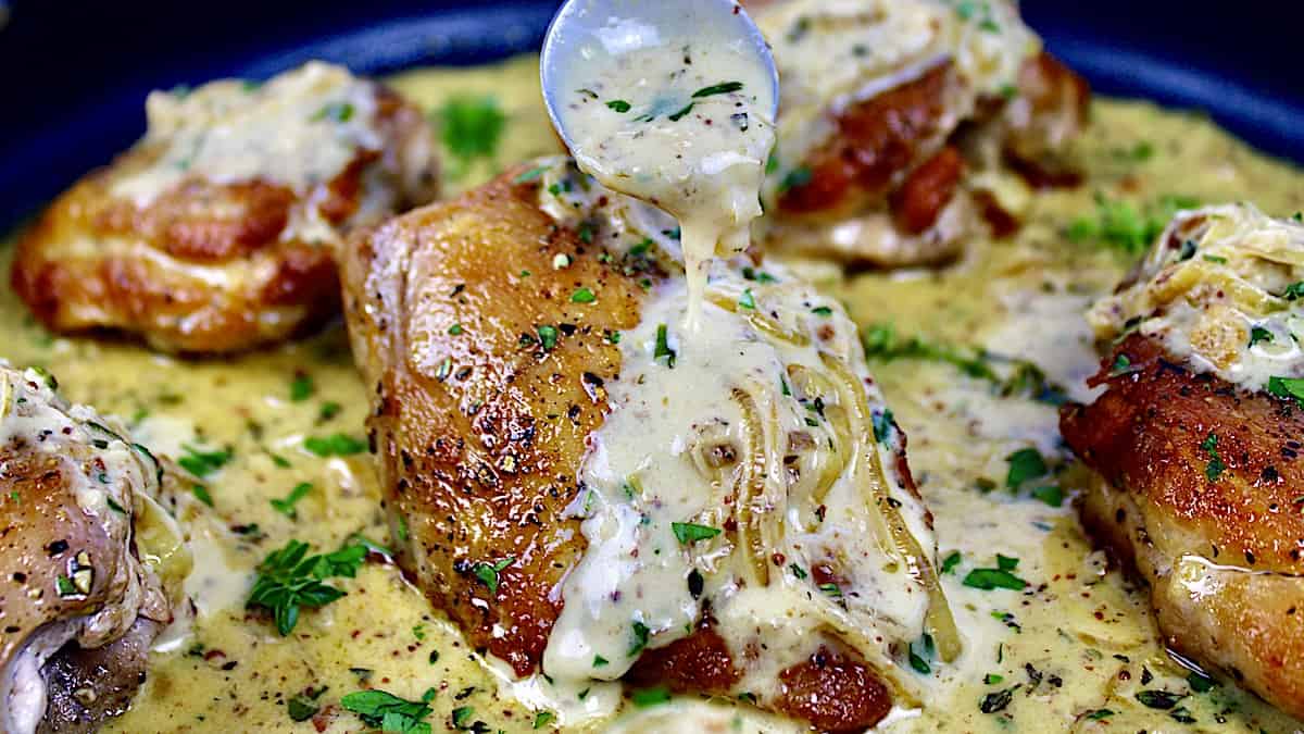 closeup up Creamy Chicken Dijon in skillet with sauce being spooned on top