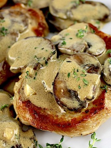 Creamy Mushroom Gravy over pork chops on white plate