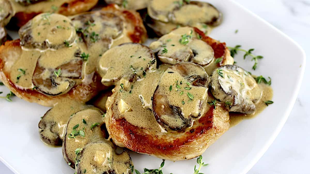 Creamy Mushroom Gravy over pork chops on white plate