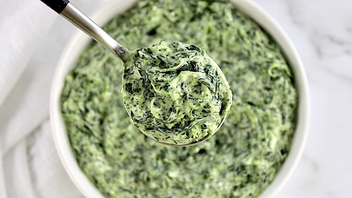 Easy Creamed Spinach held up in spoon over white bowl