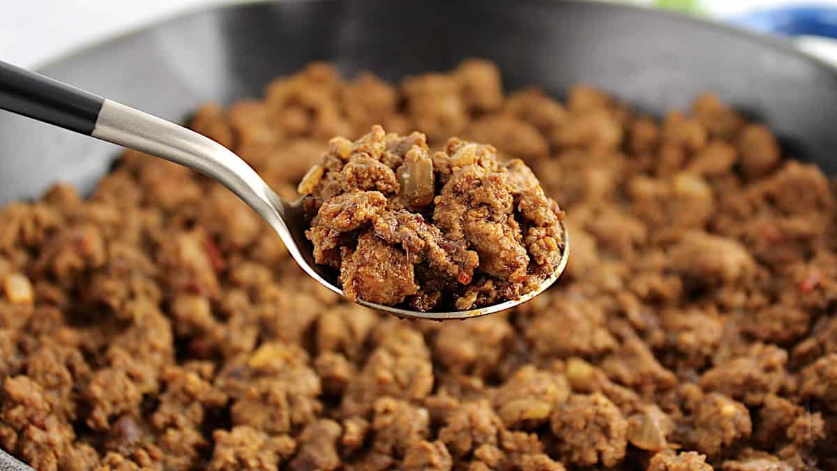 Easy Taco Meat in spoon held up over skillet with more taco meat