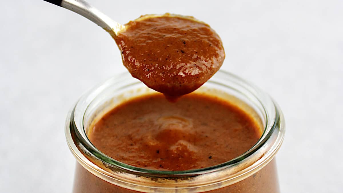 Enchilada Sauce being spooned out of open glass jar