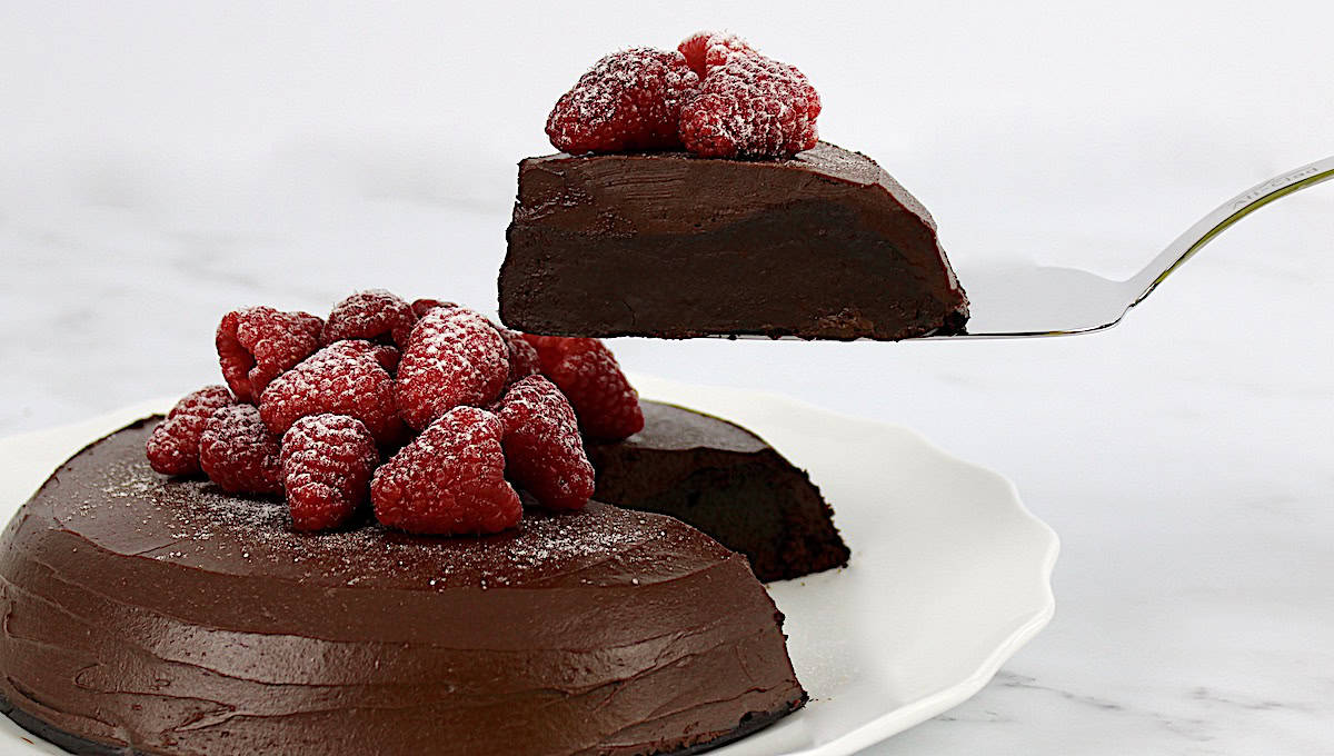 slice of Flourless Chocolate Cake being held up on silver cake server