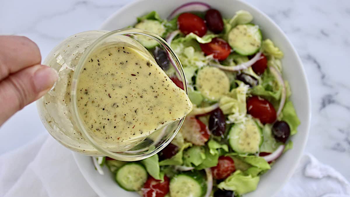 Italian Dressing being poured over salad