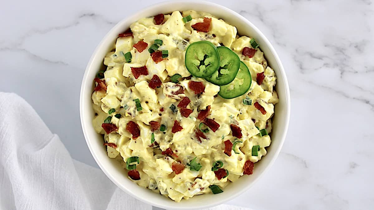 Jalapeno Popper Egg Salad in white bowl with 3 sliced jalapenos on top