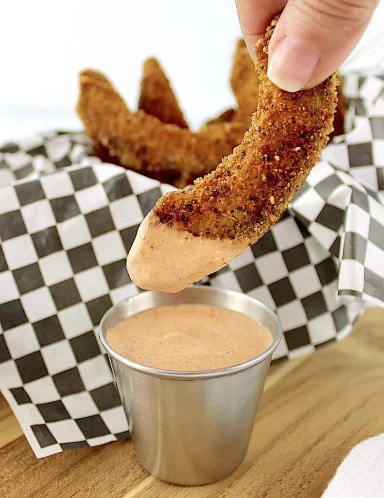 avocado fry being dipped into zesty dipping sauce