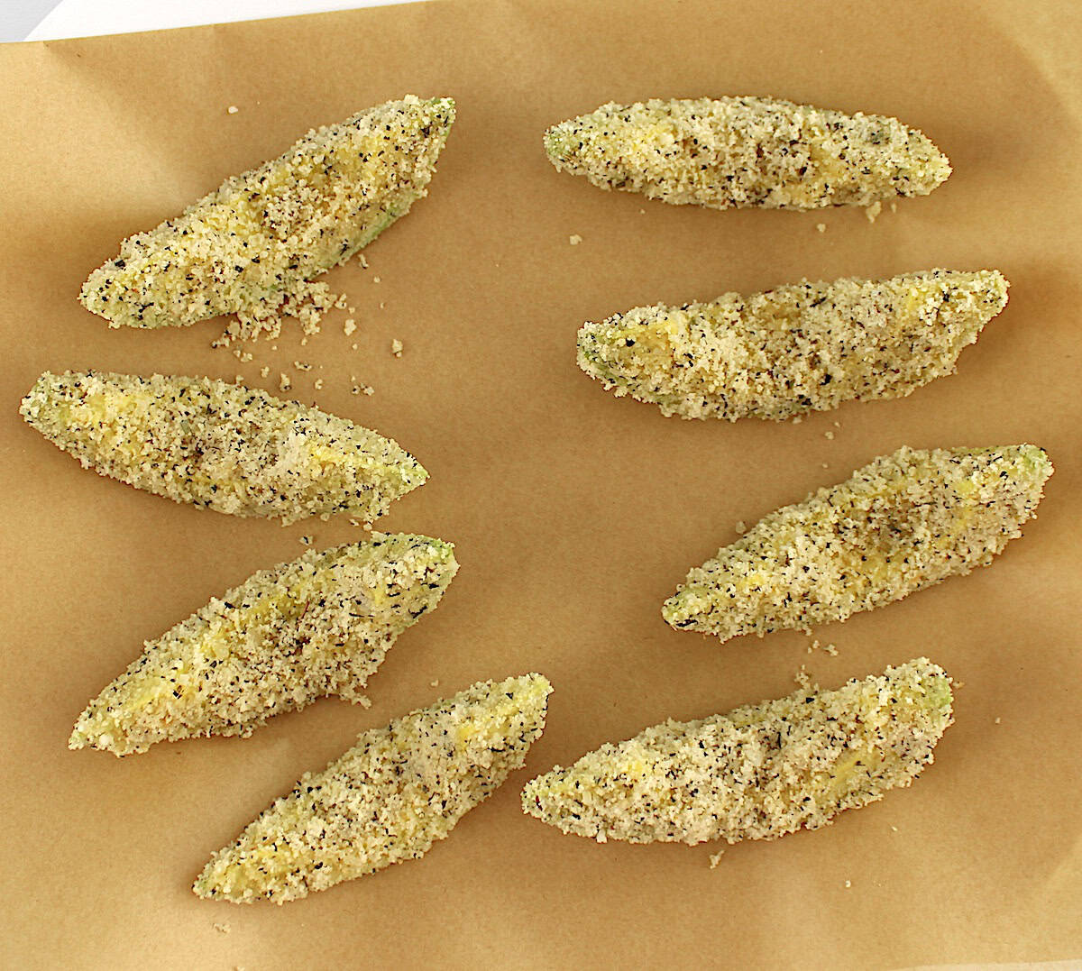 breaded avocado fries uncooked on parchment paper