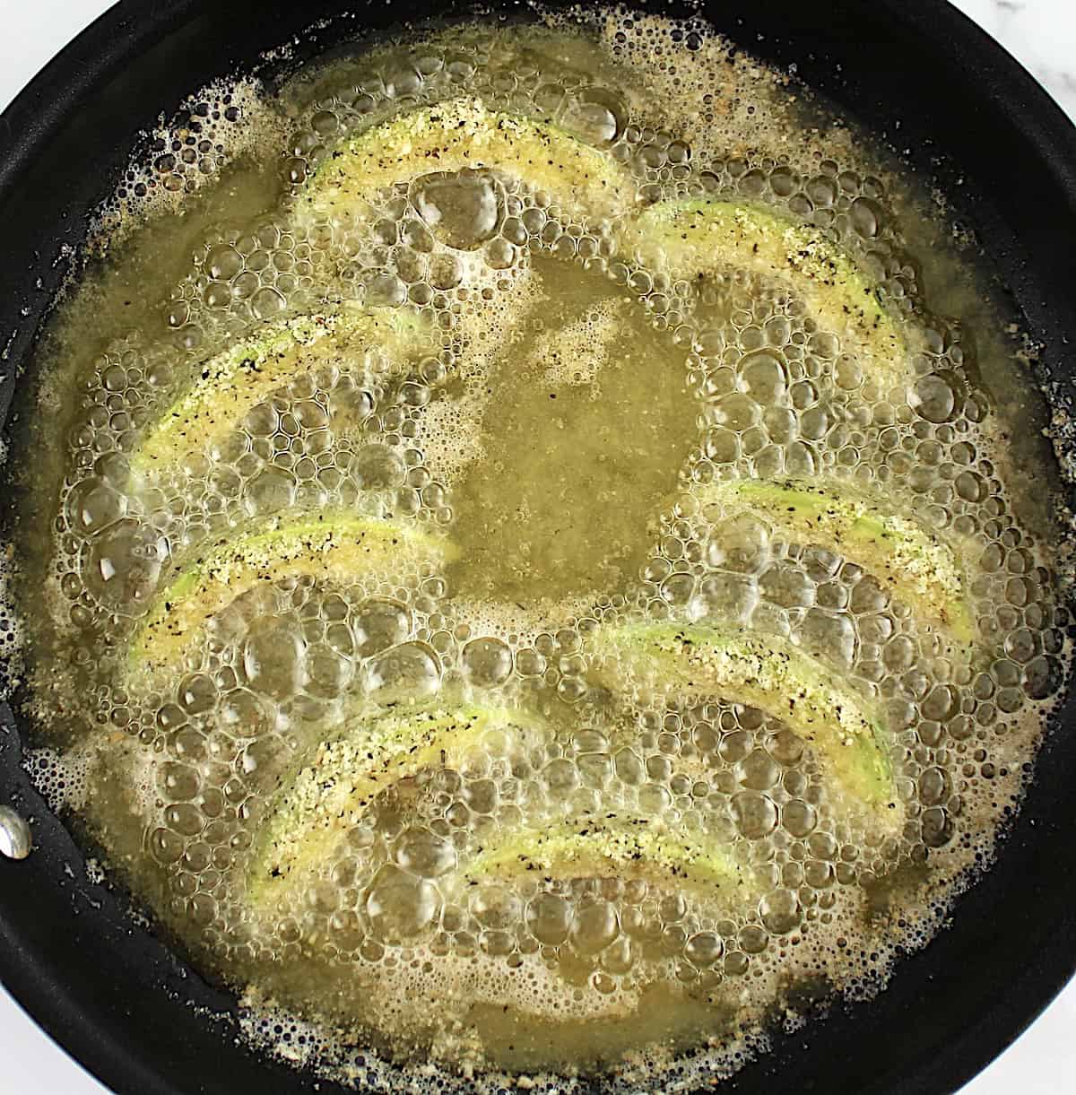 avocado fries frying in a skillet with oil