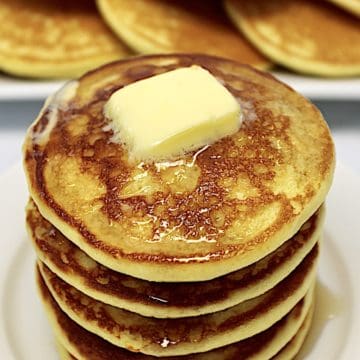 stack of Keto Buttermilk Pancakes on white plate with pad of butter on top