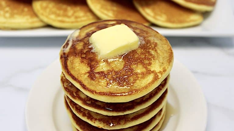 stack of Keto Buttermilk Pancakes on white plate with pad of butter on top