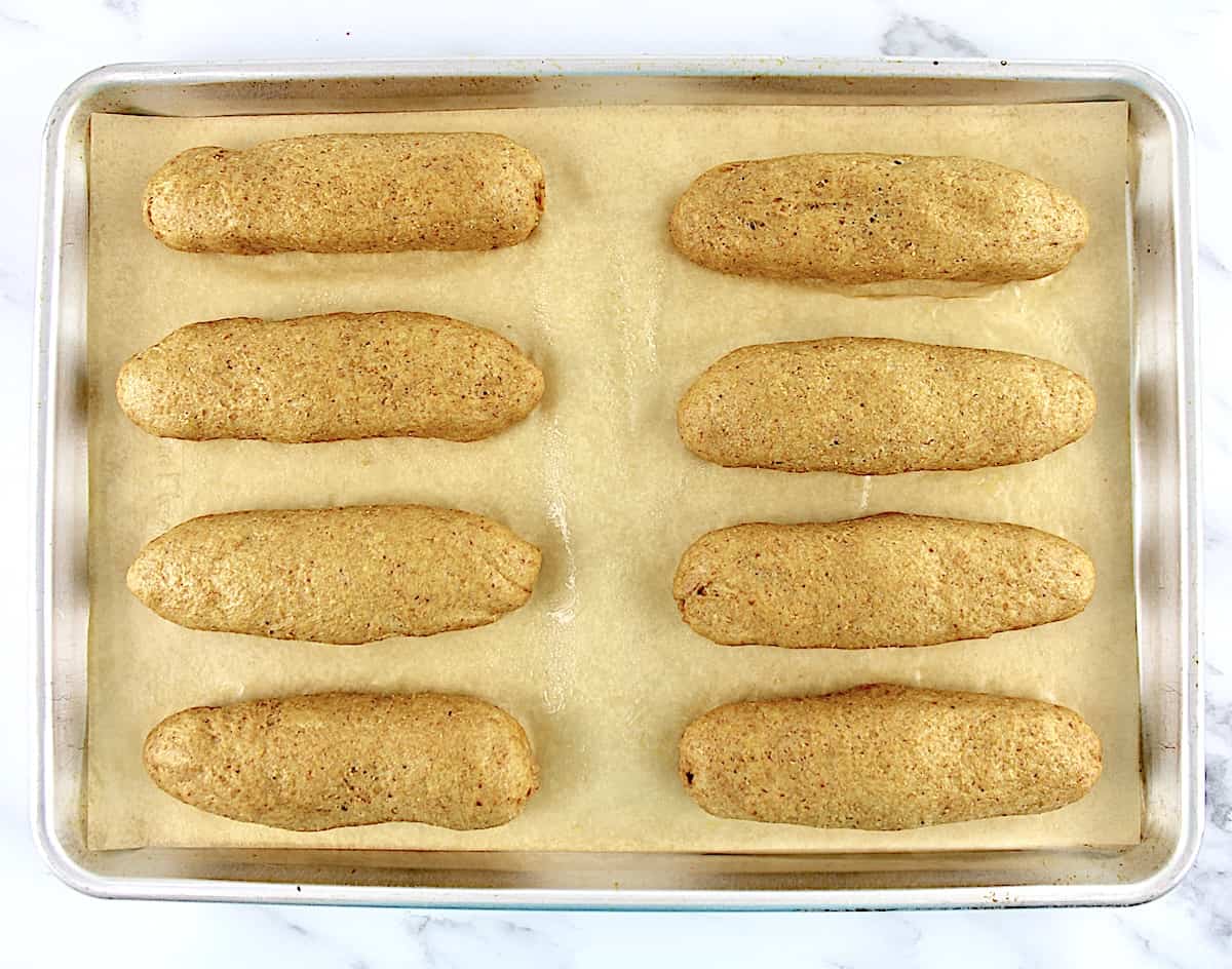 8 hot dog buns dough lined up on baking sheet lined with parchment paper