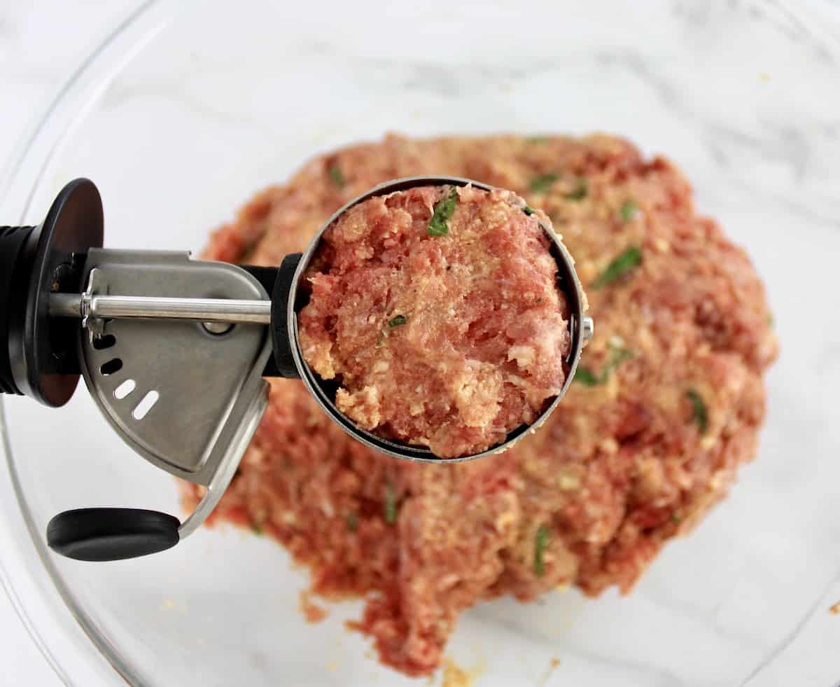 Keto Italian Meatball mix in ice cream scoop held over a mixing bowl