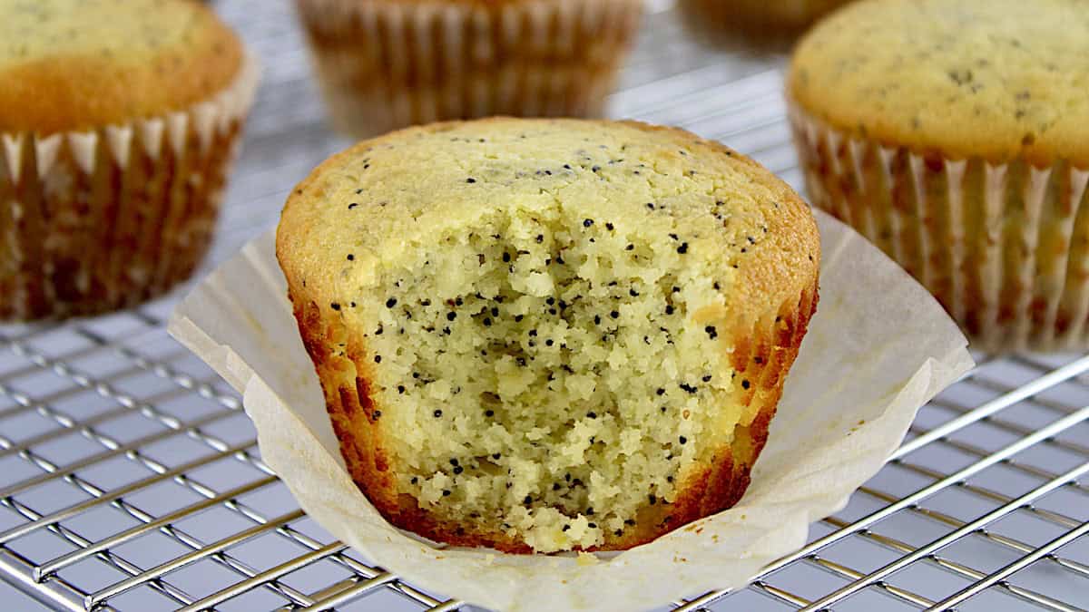 closeup of Keto Lemon Poppy Muffin on cooling rack with bite missing