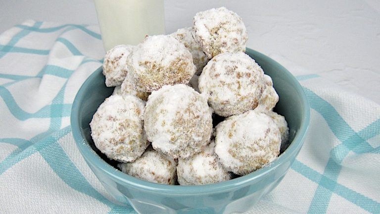 Keto Maple Pecan Snowball Cookies in teal bowl with milk in background