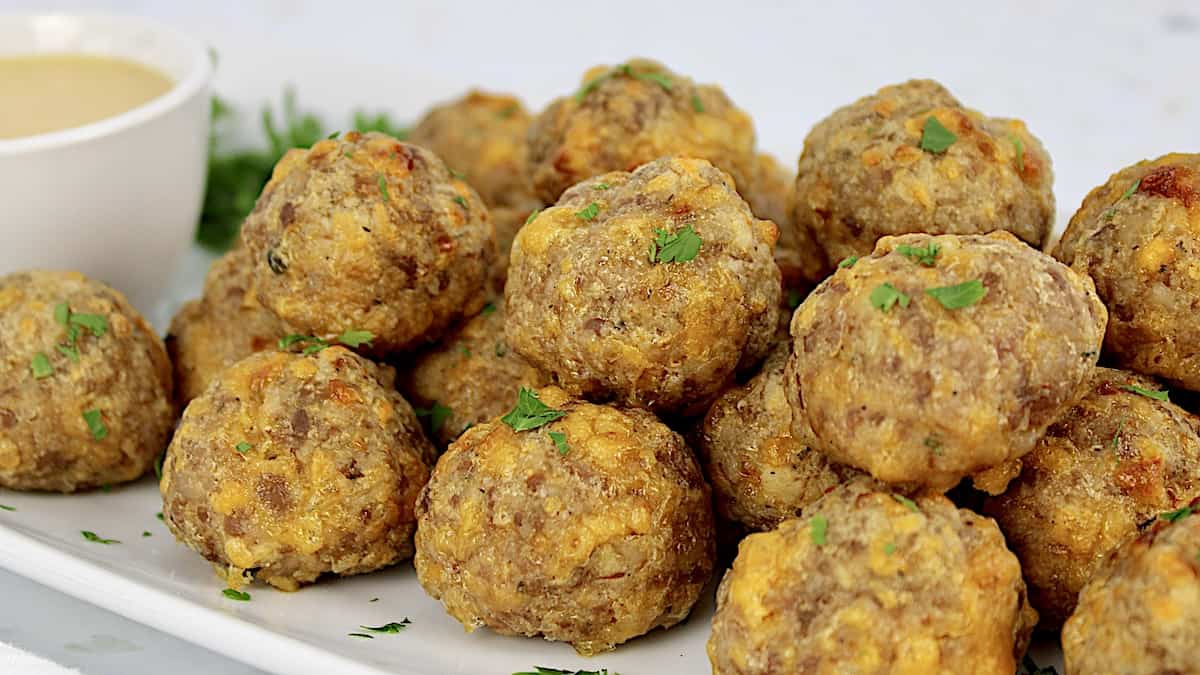 Keto Sausage Balls on white plate piled up with chopped parsley