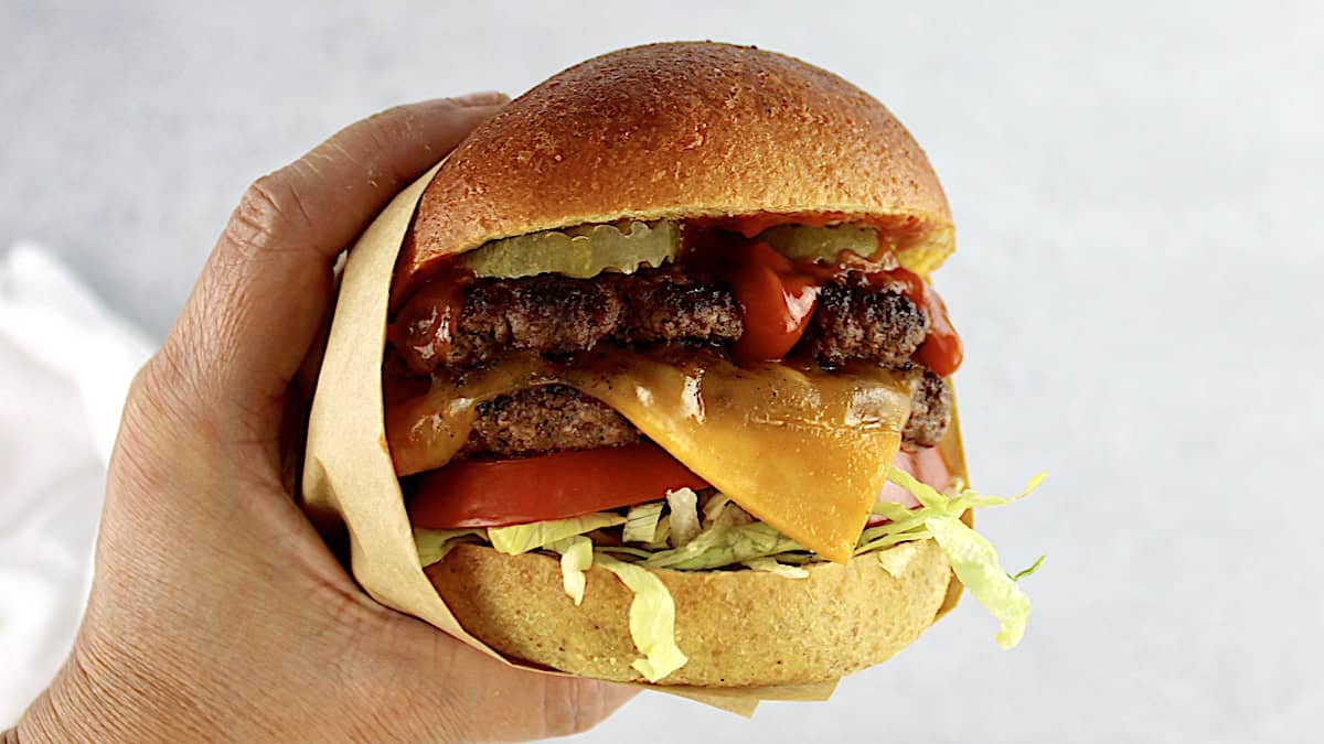 Keto Smash Burger held up and partially wrapped in parchment paper