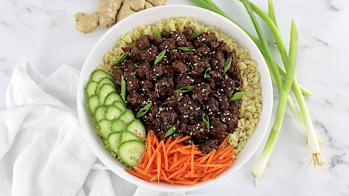 Korean Beef Bowl with sliced cucumber and shredded carrots in white bowl