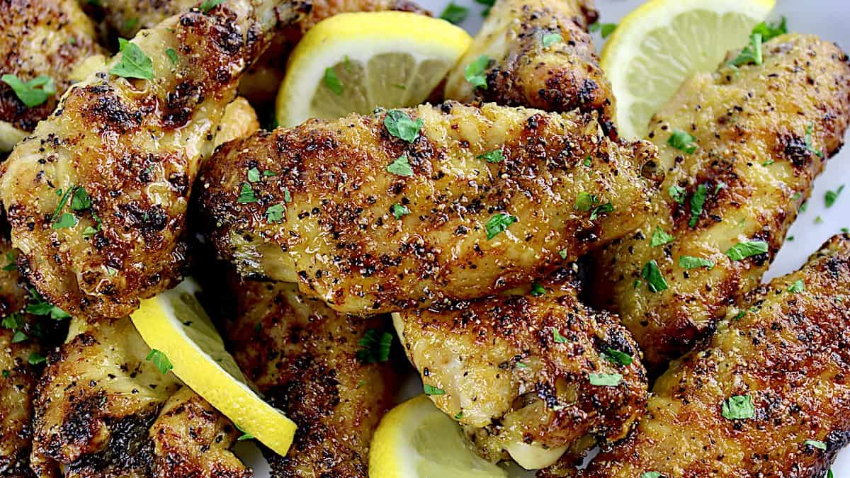 closeup ofLemon Pepper Chicken Wings with lemon slices and chopped parsley