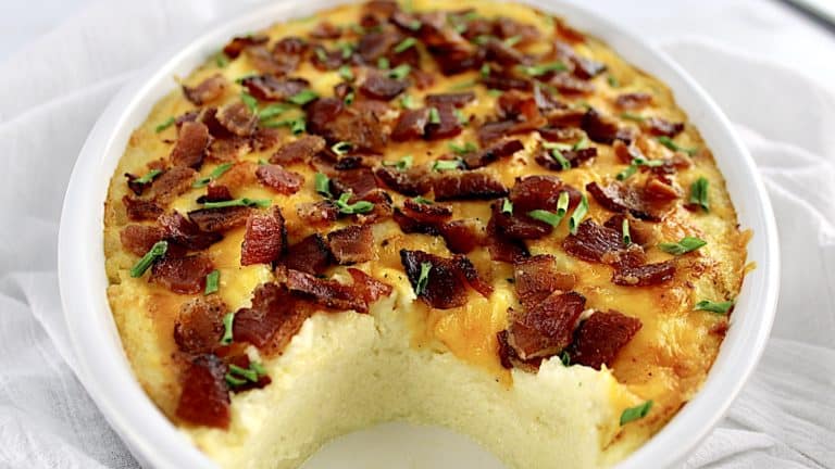closeup of Loaded Cauliflower Casserole with piece missing and crumbled bacon on top
