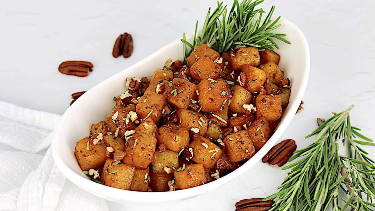 maple roasted butternut squash in white bowl with fresh rosemary garnish