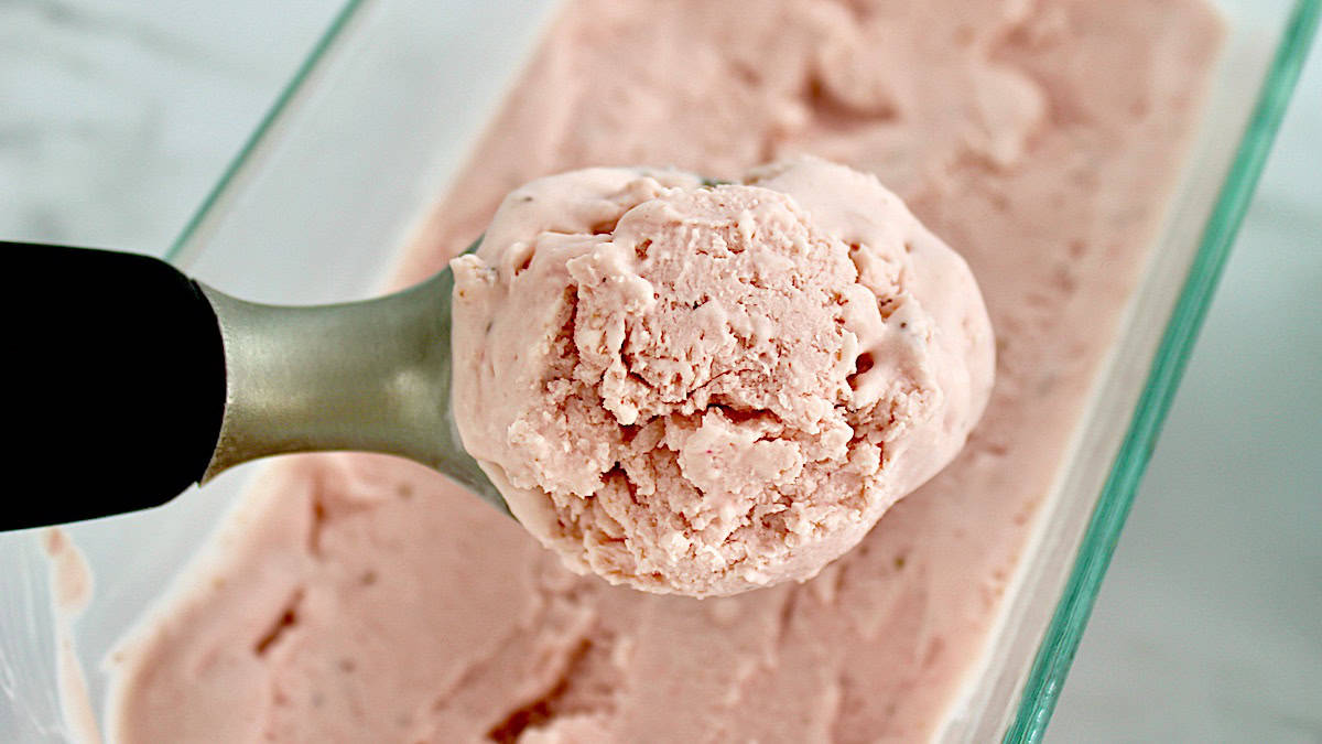 No Churn Strawberry Ice Cream being scooped out of glass container