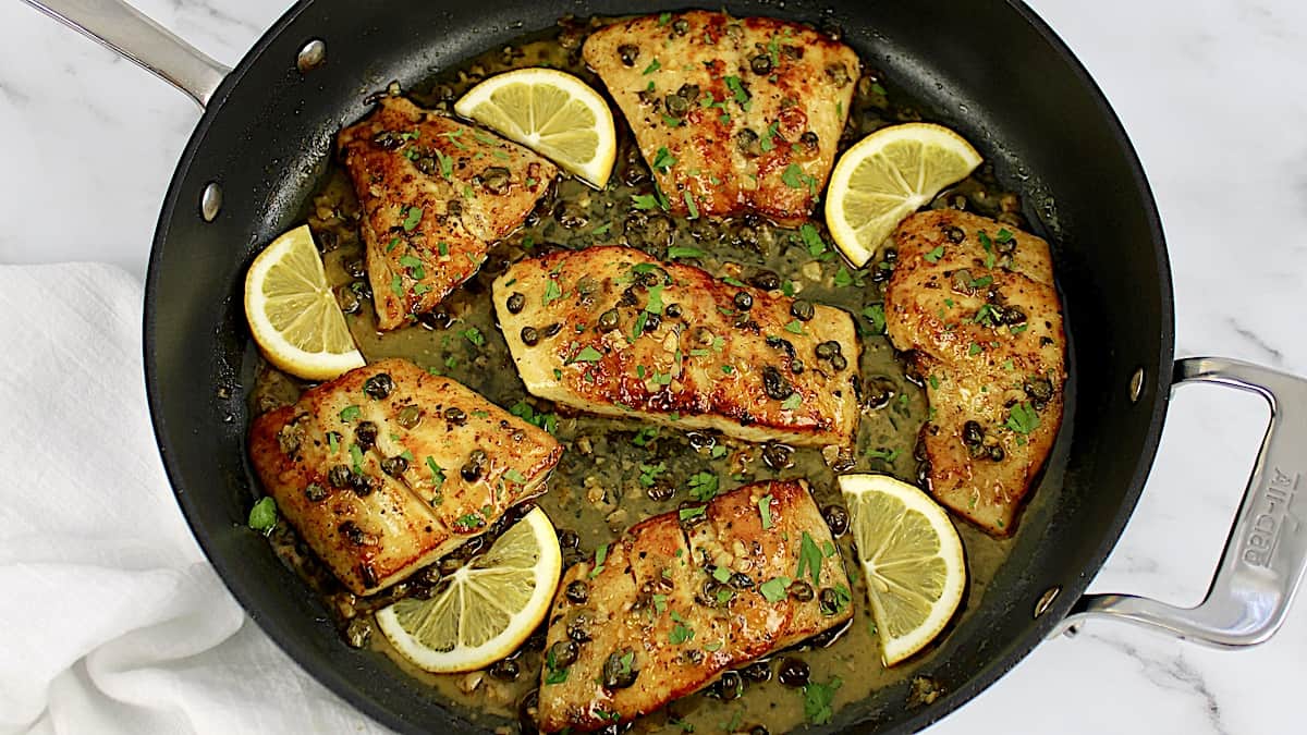 Red Snapper with Lemon Caper Sauce in skillet with lemon slices