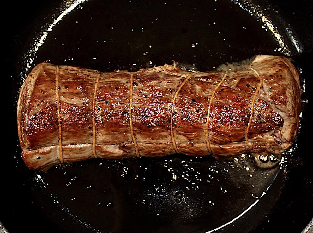 Roast Beef Tenderloin with kitchen twine searing in cast iron skillet