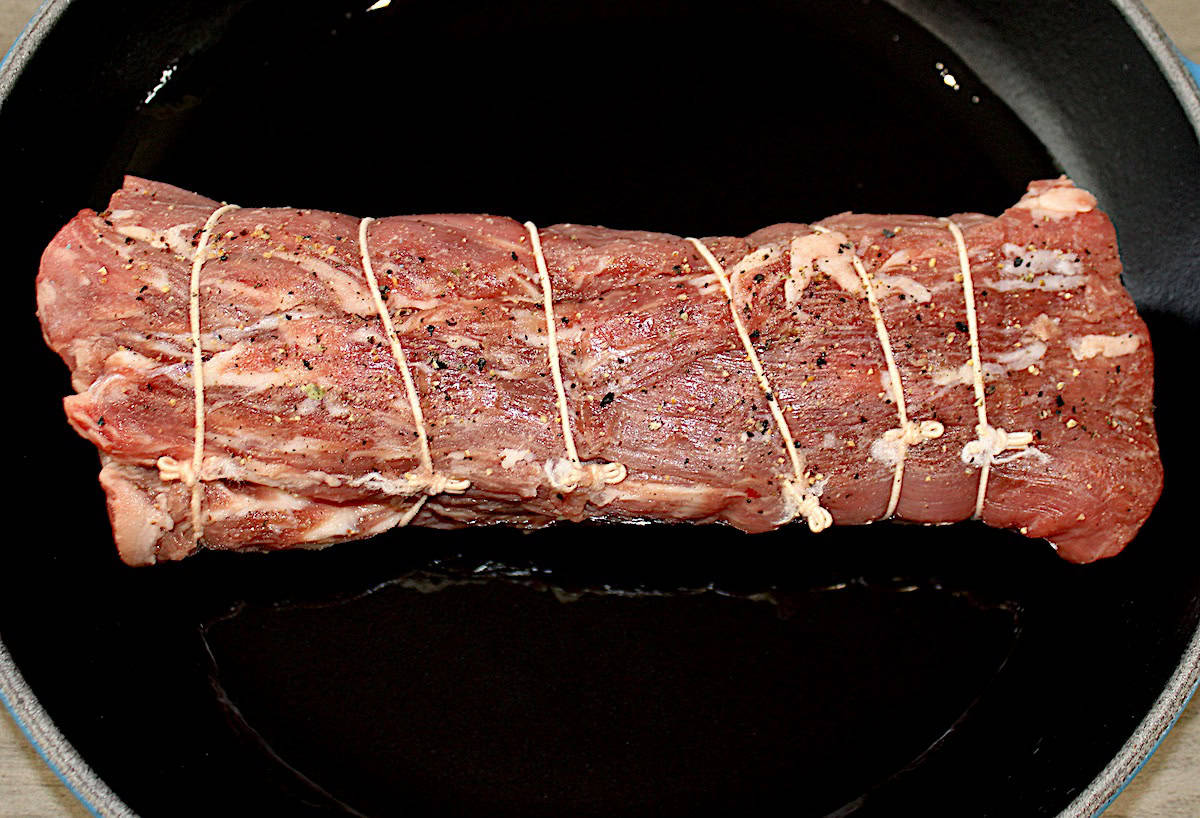 beef tenderloin with kitchen twine in cast iron skillet