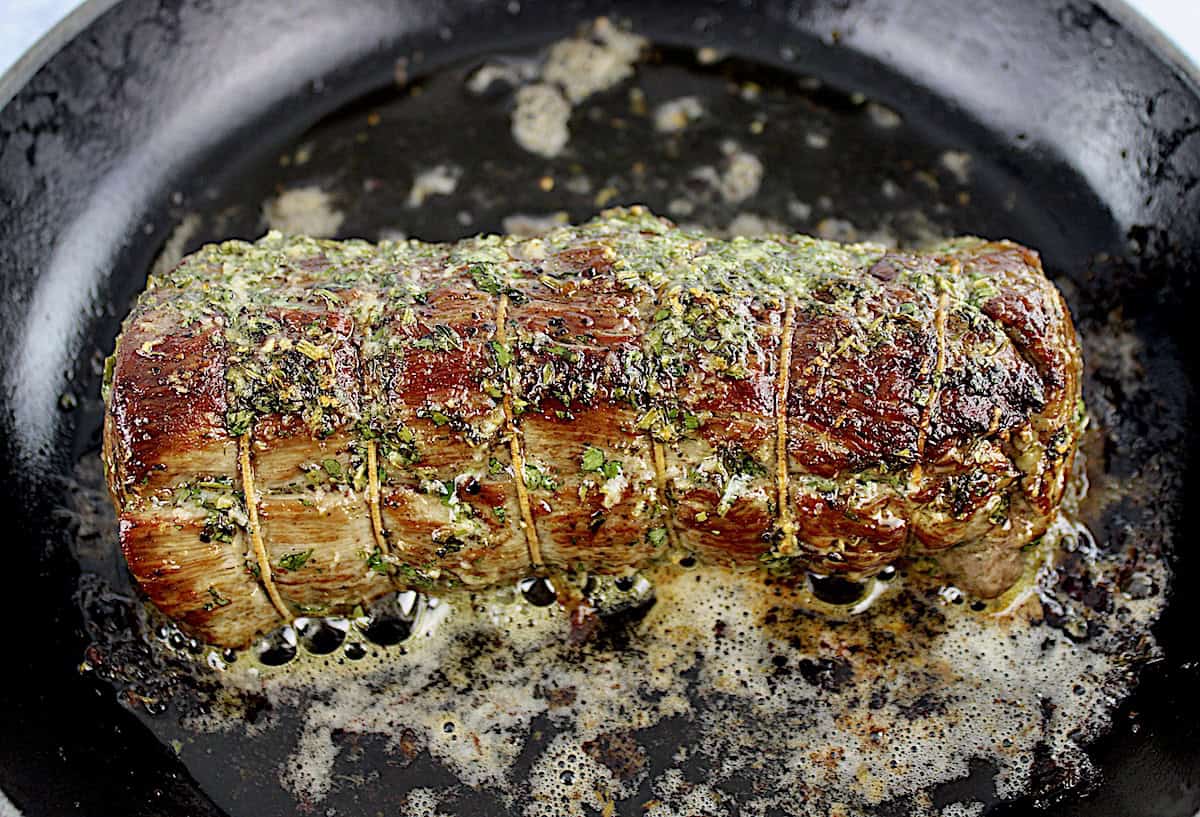 Roast Beef Tenderloin with herb butter all over in skillet