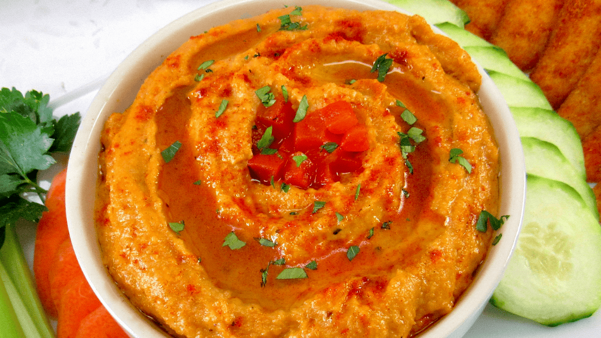 Roasted Pepper Hummus in white bowl with chopped peppers and parsley on top