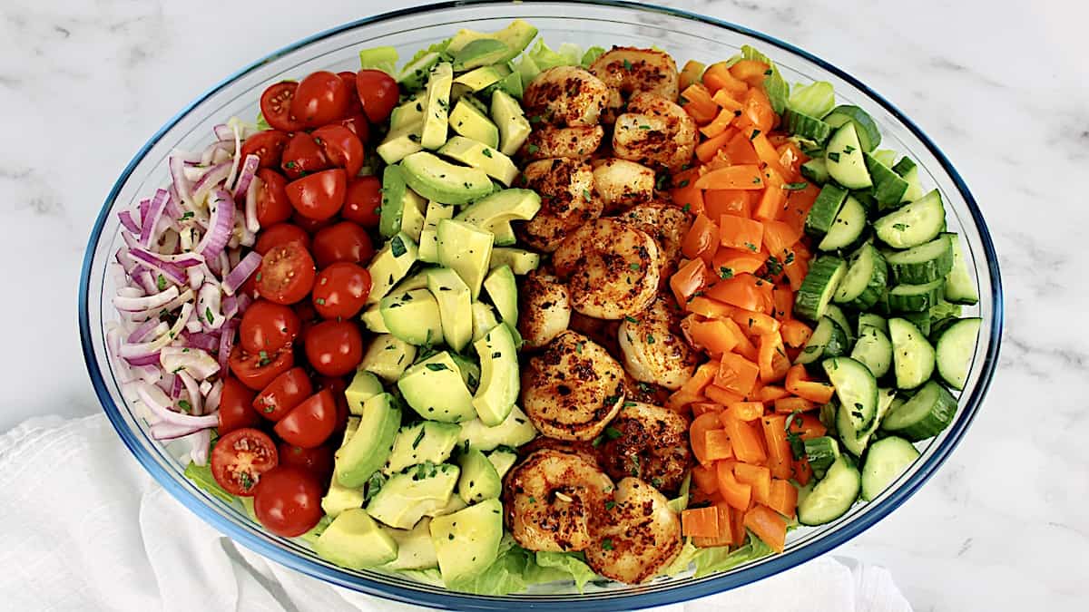 Shrimp Avocado Salad in oval glass bowl with ingredients arranged in vertical rows over lettuce