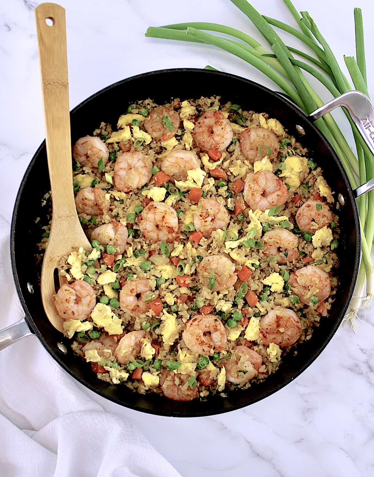 overhead view of Shrimp Cauliflower Fried Rice with wooden spoon in skillet