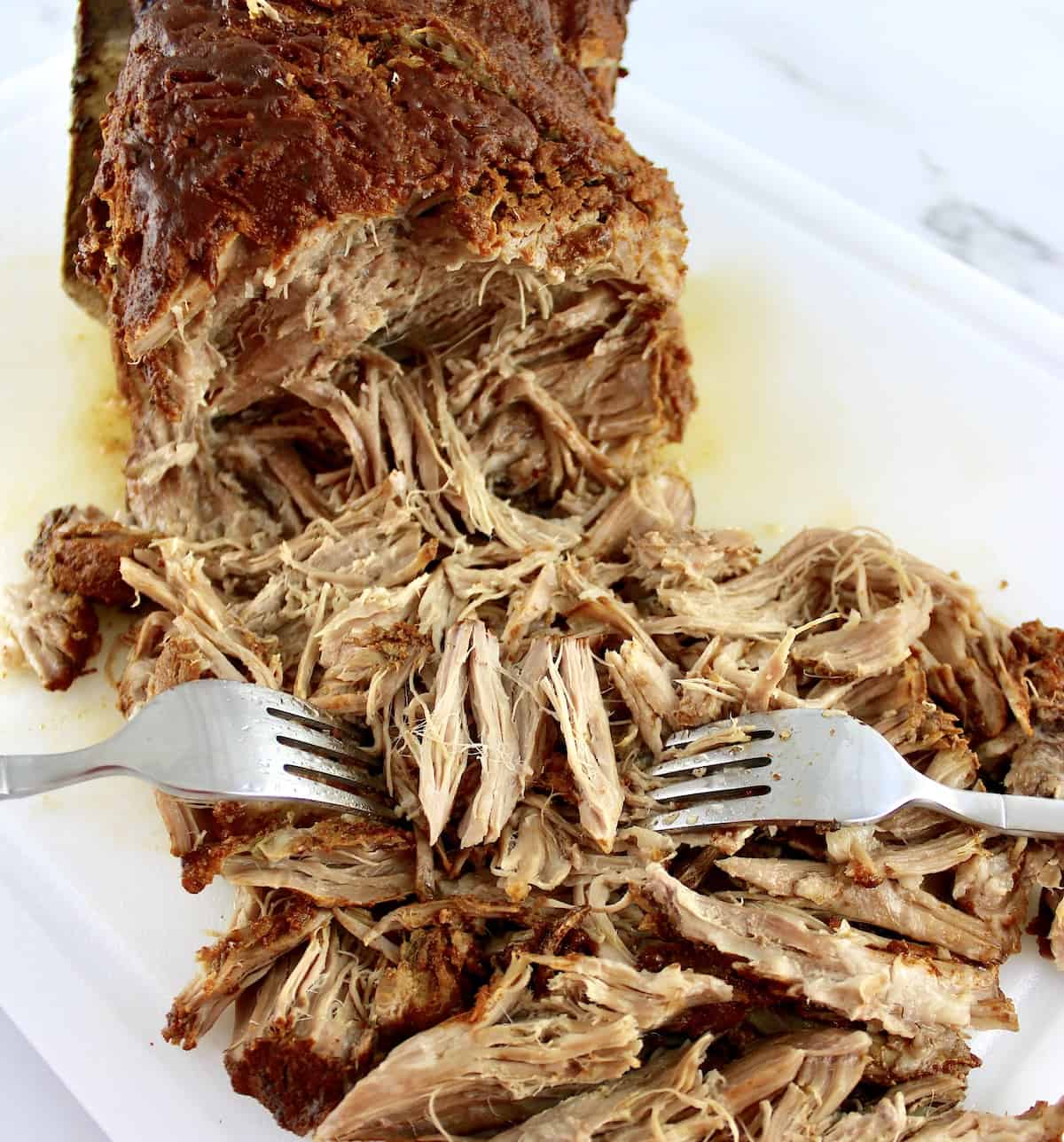 2 forks shredding cooked pork shoulder