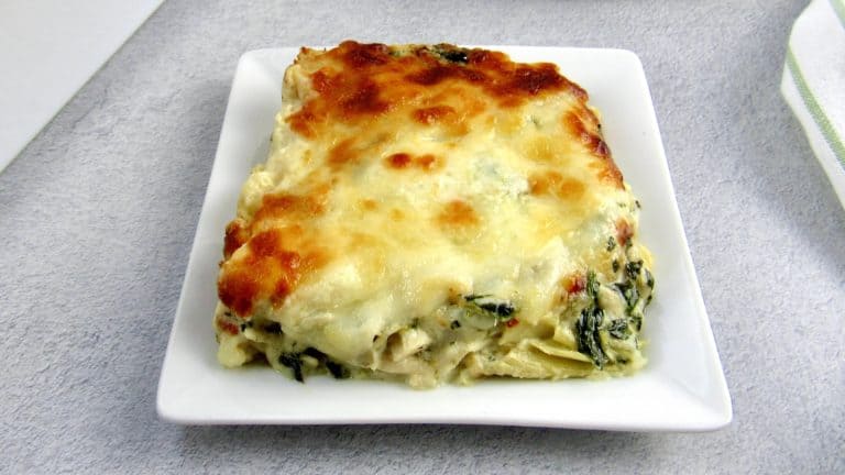 closeup of Spinach Artichoke Chicken Casserole slice on white square plate